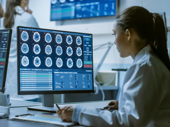 female-medical-research-scientist-working-with-brain-scans-on-her-personal-computer-writing-down-data-in-a-clipboard-modern-laboratory-working-on-neurophysiology-science-neuropharmacology