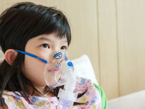 sick little asian girl inhalation with nebulizer for respiratory treatment