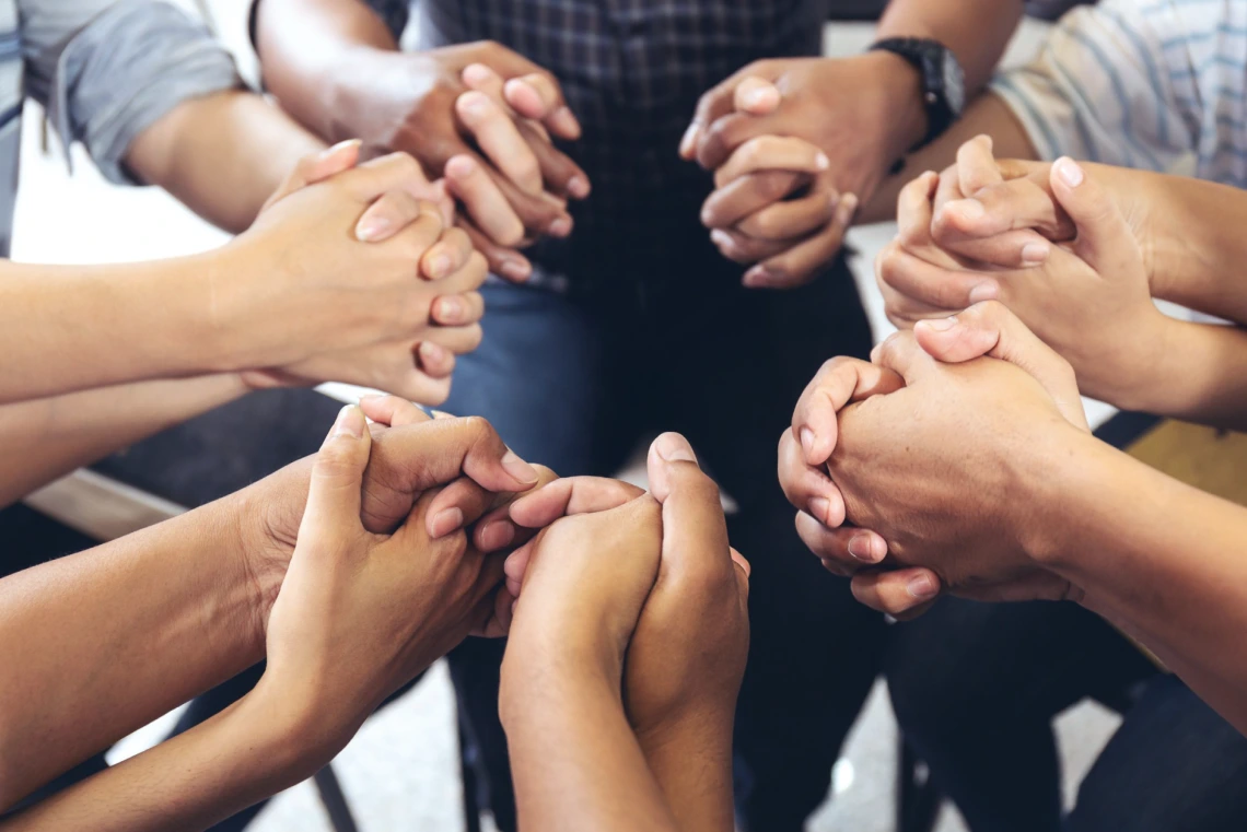 Close-up image of several people holding hands 