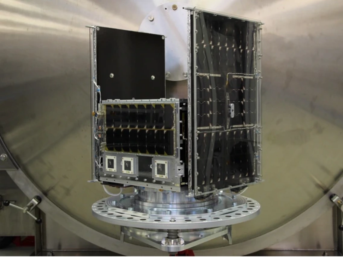 The completed spacecraft bus for the NASA Aspera mission, sitting on a table. Large solar panels provide the satellite with power. 